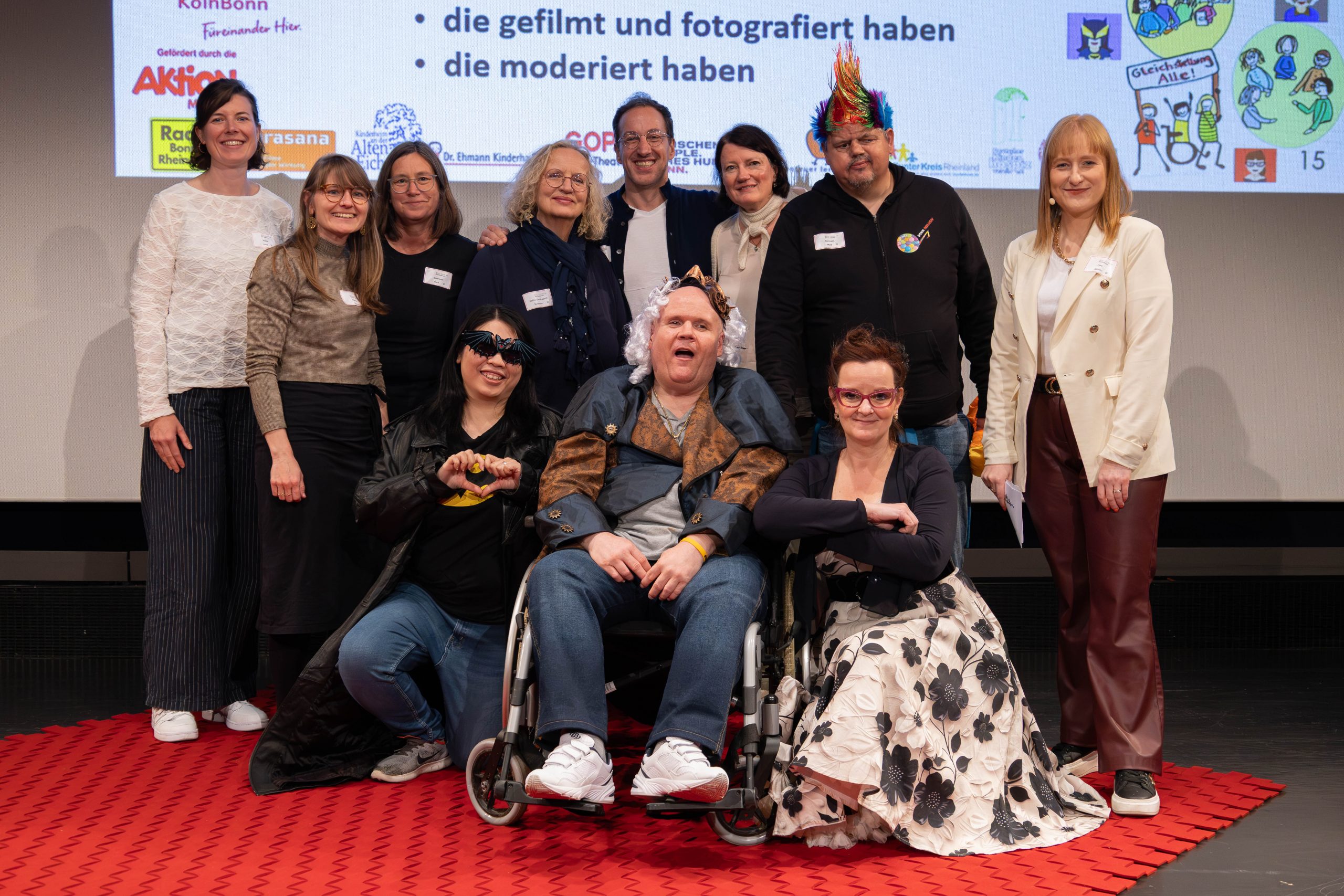 Gruppenfoto Menschen mit und ohne Behinderung. Beteiligte der Konferenz lächeln gemeinsam in die Kamera.